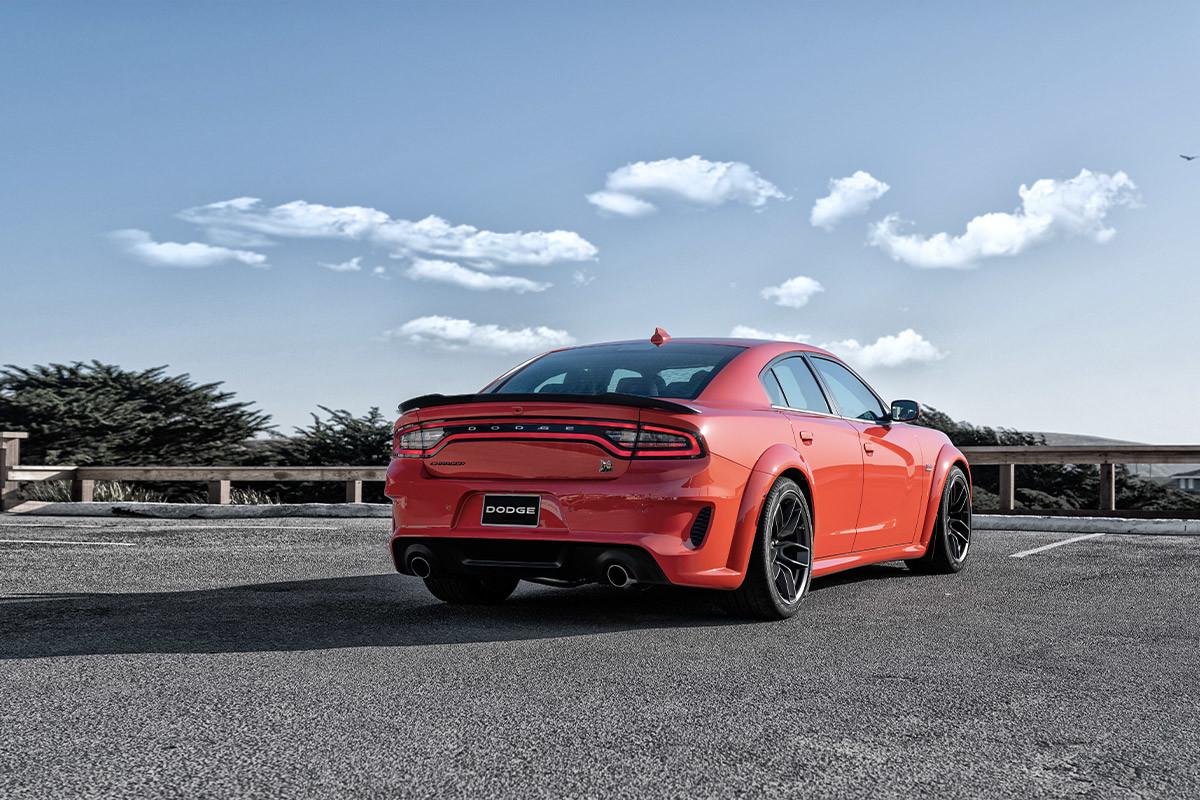 Un angle arrière d’une Dodge Charger rouge garée dans une aire de stationnement.