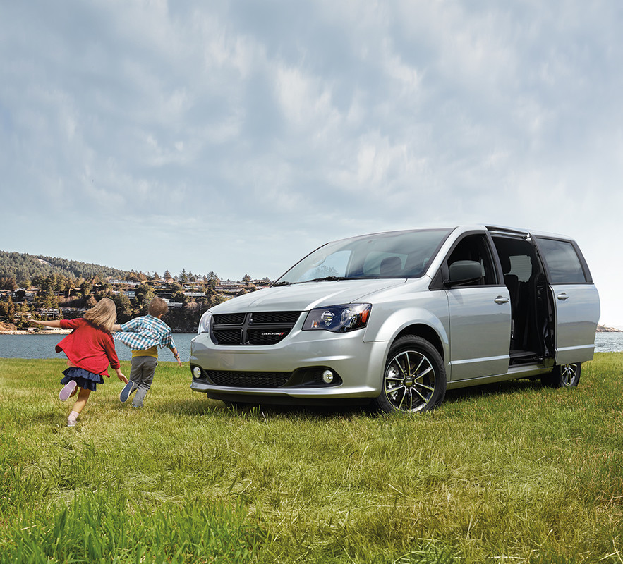 Kids running around Silver 2020 Dodge Grand Caravan on a field