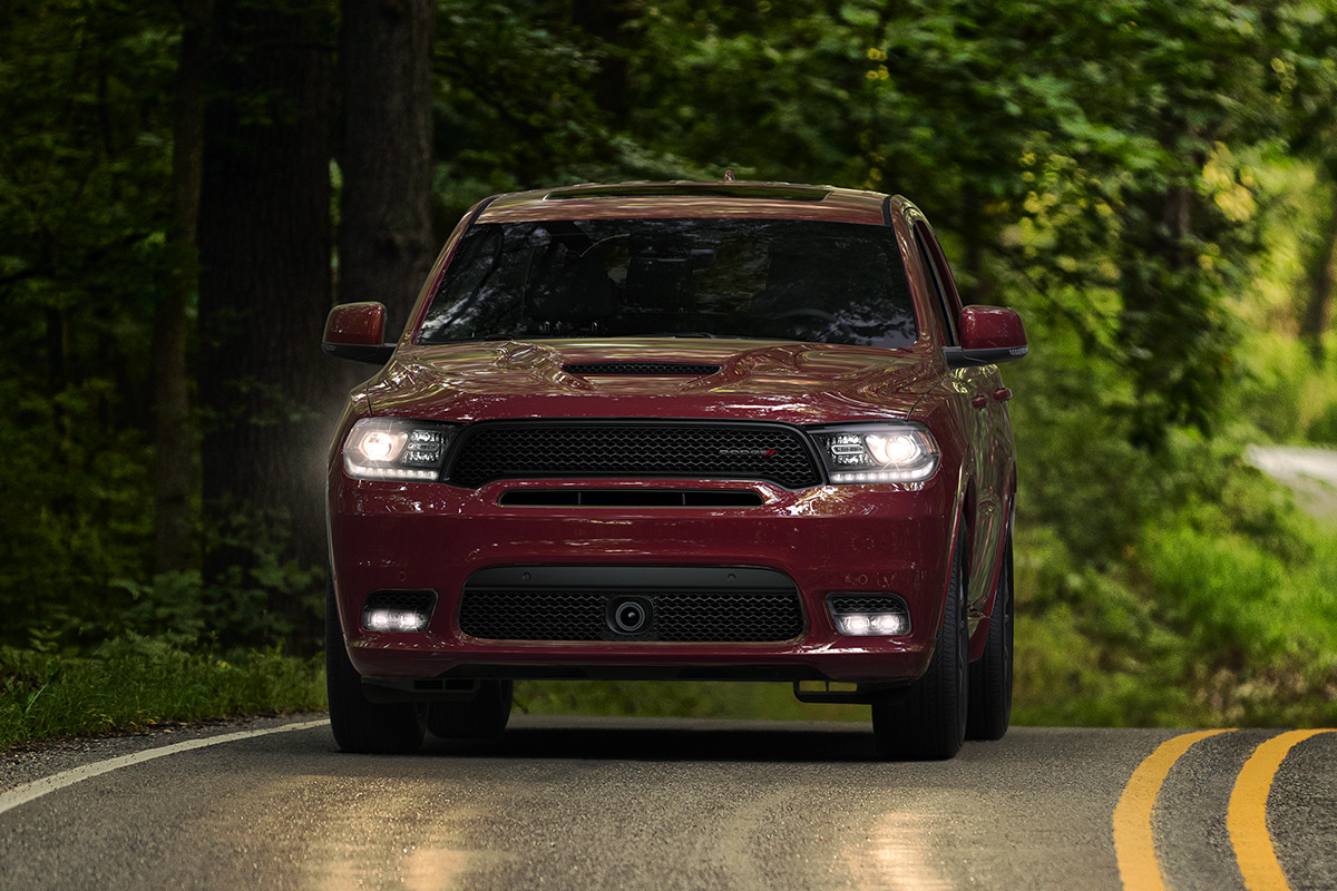 Un Dodge Durango 2019 rouge roulant sur une route pavée dans la forêt.