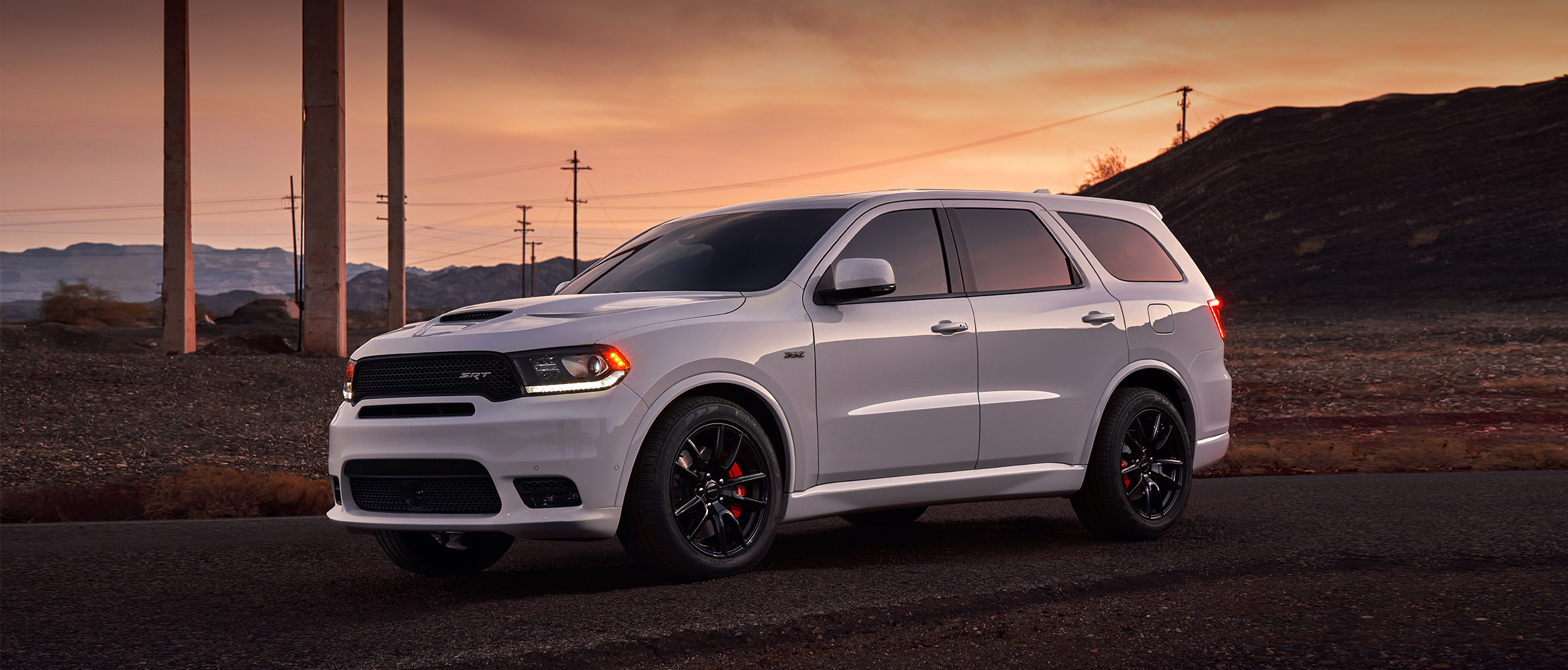 Un Dodge Durango 2019 blanc stationné sur une route pavée en banlieue.