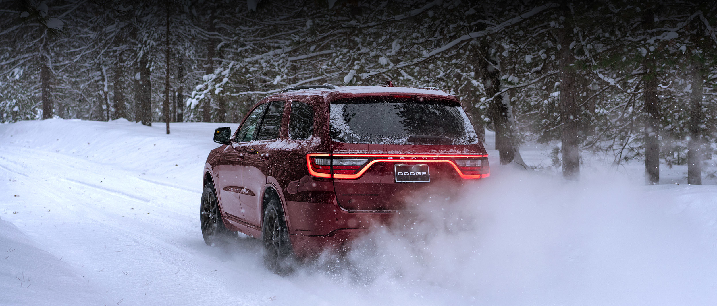 Rear view of the red 2020 Dodge Durango driving through a snowy forest
