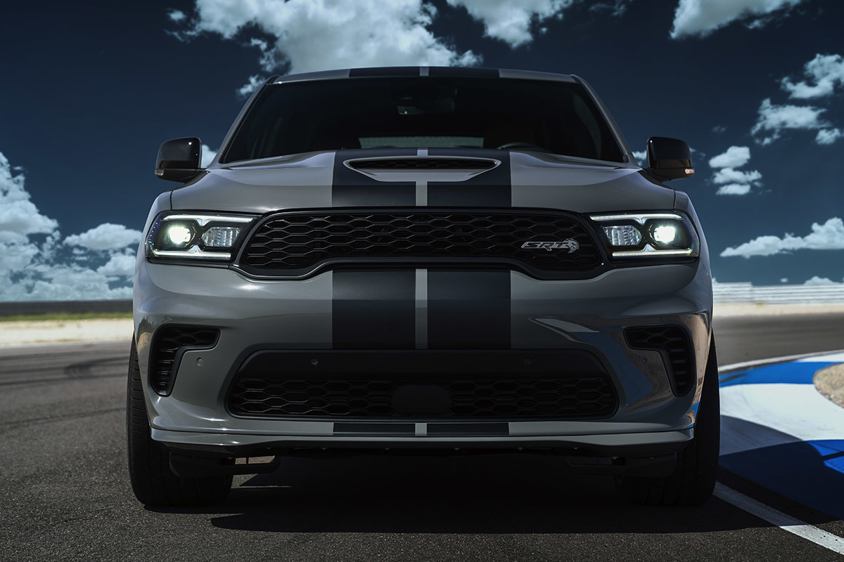 Vue de face d’un Dodge Durango gris garé sur une piste de course avec les phares allumés.