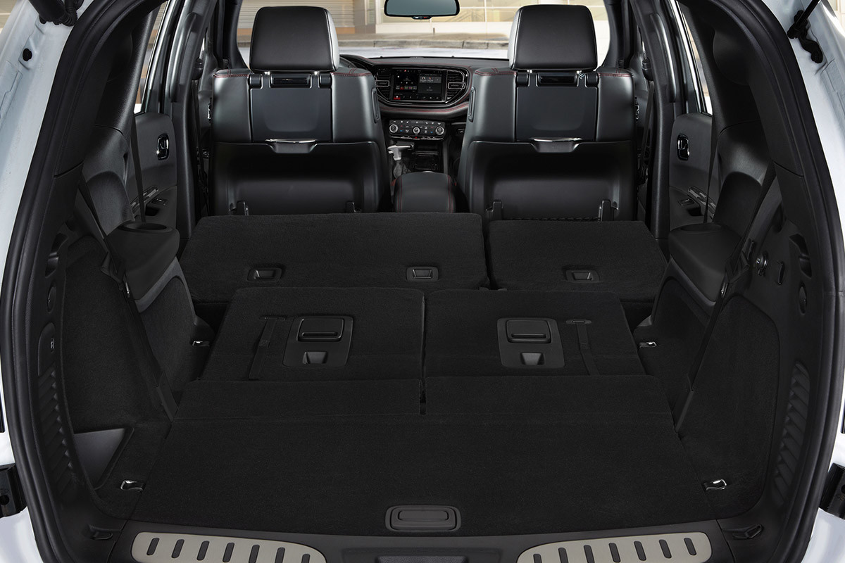 Vue arrière du Dodge Durango avec l’arrière ouvert, révélant deux rangées de sièges rabattus à l’intérieur pour laisser place à l’espace utilitaire.