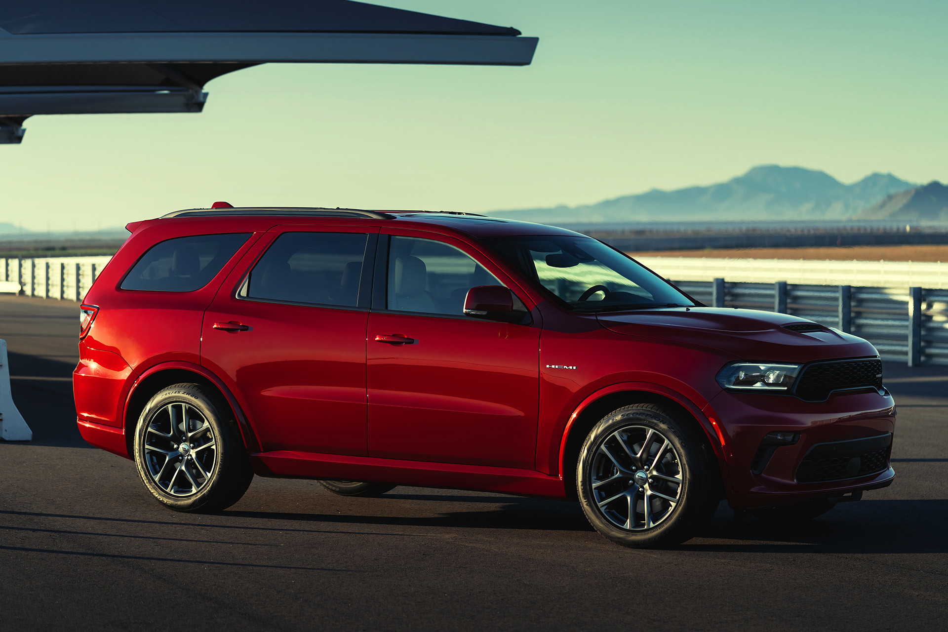 Vue latérale d’un Dodge Durango rouge garé sur la chaussée avec des montagnes au loin.