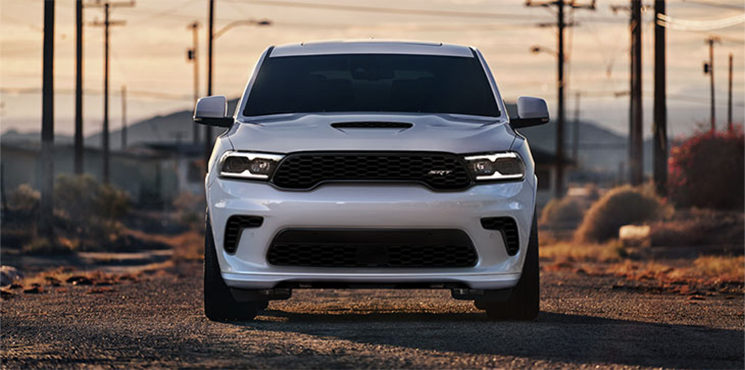 Dodge Durango blanc roulant au coucher du soleil à travers les routes de campagne.