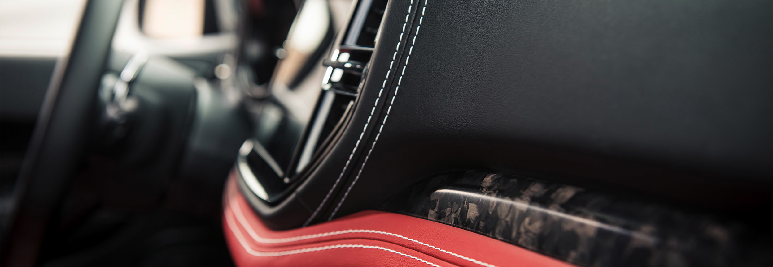 Close up of the passenger side red and black interior with focus on the white stitching