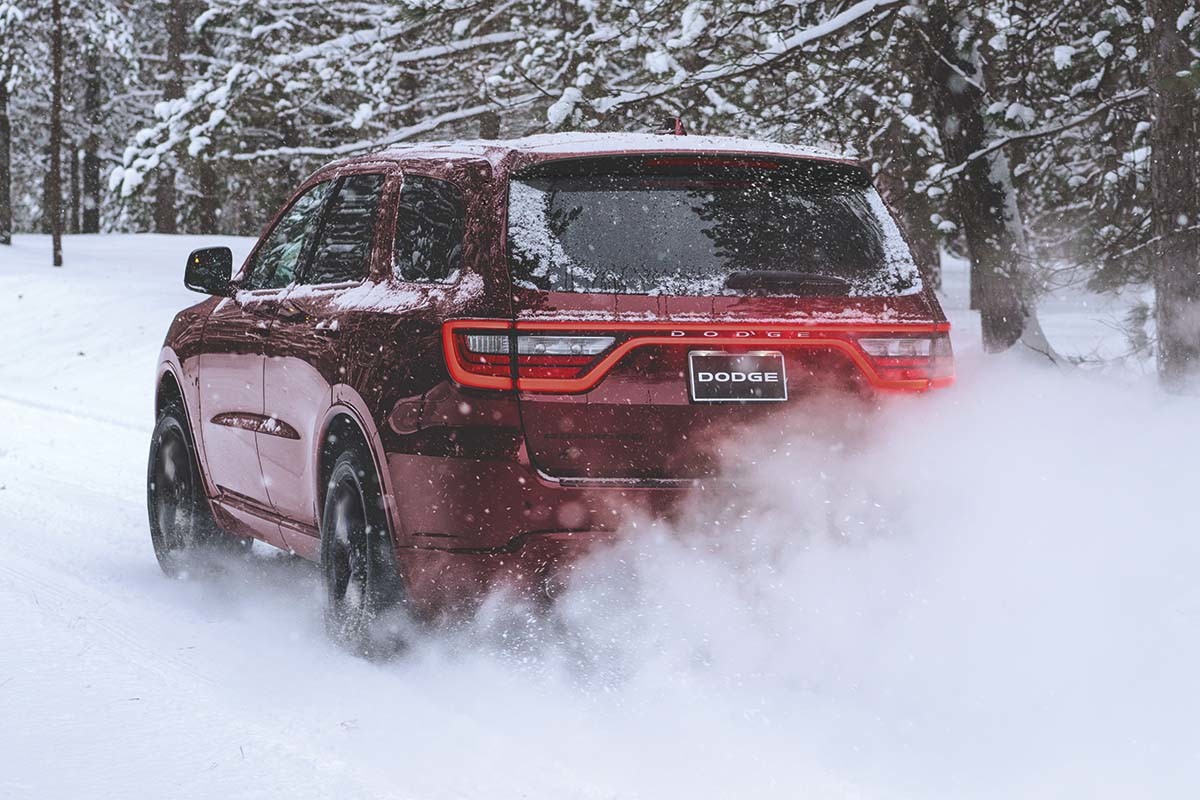 A red 2022 Dodge Durango driving on a snowy road in a forest