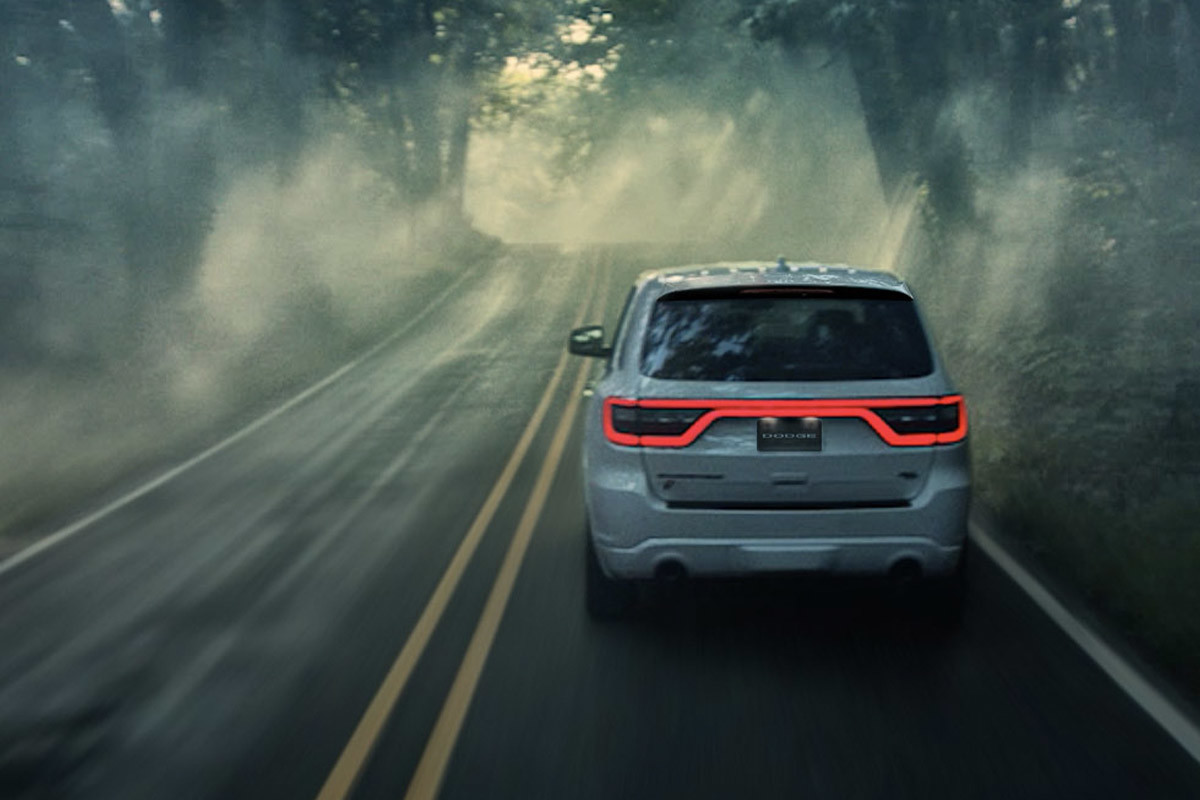 L’arrière d’un Dodge Durango 2022 blanc roulant sur une route par temps brumeux