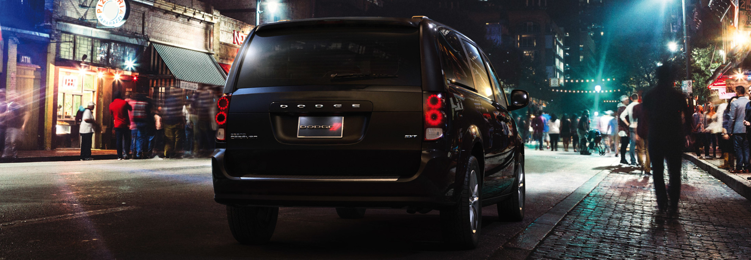 Dodge Grand Caravan 2020 noire roulant dans une rue animée de la ville, la nuit.