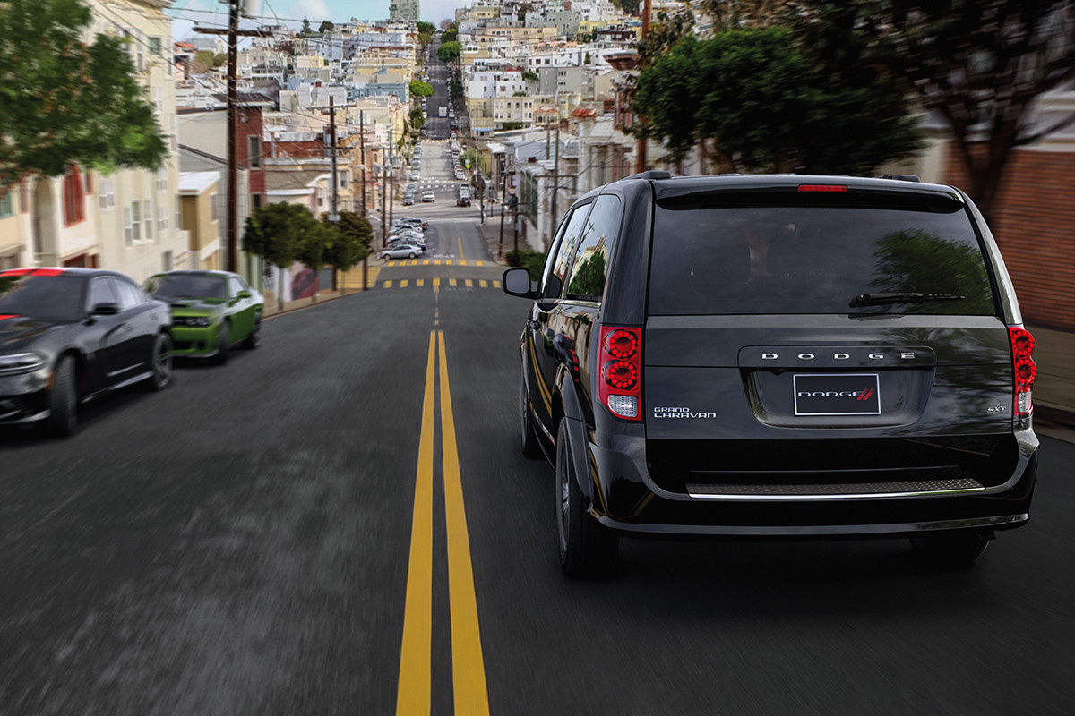 Rear view of a black 2020 Dodge Grand Caravan driving down a city street