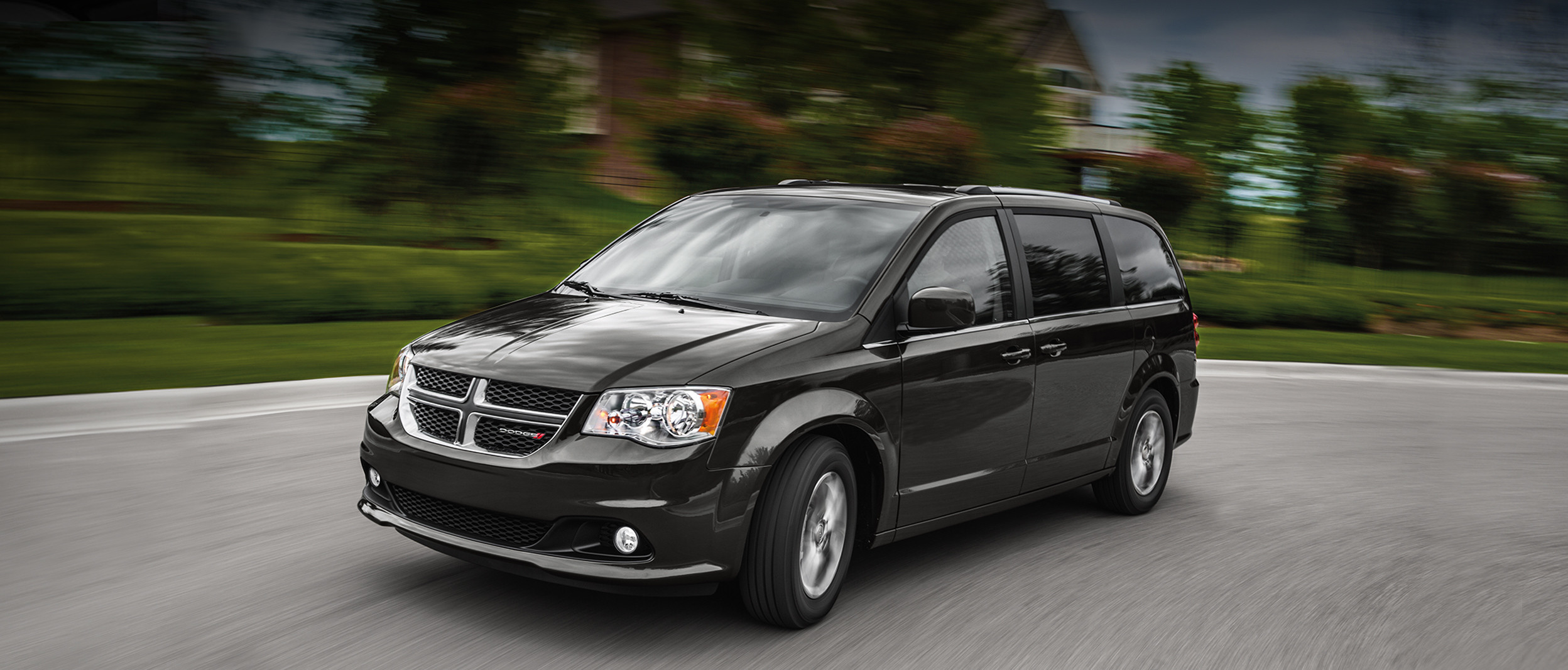 Front view of a grey 2020 Dodge Grand Caravan driving down a residential street