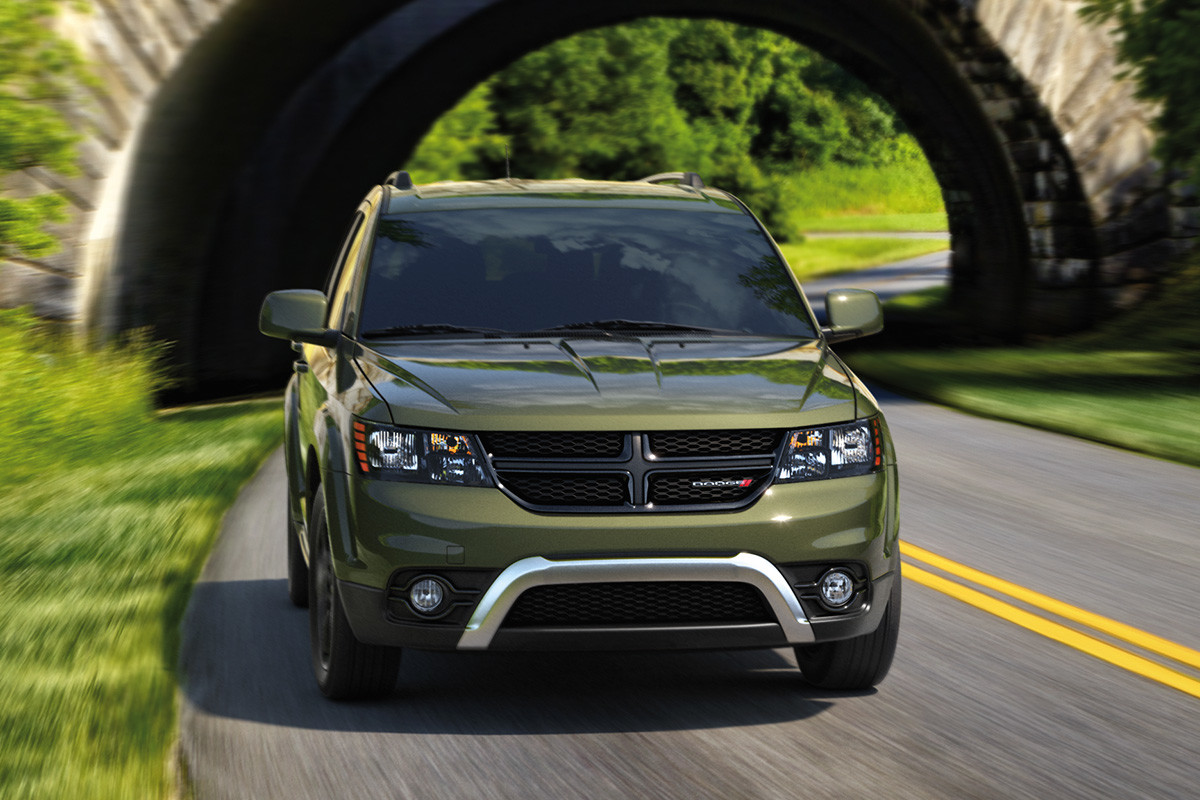 Green 2019 Dodge Journey being driven on a paved road through grassy mountains.