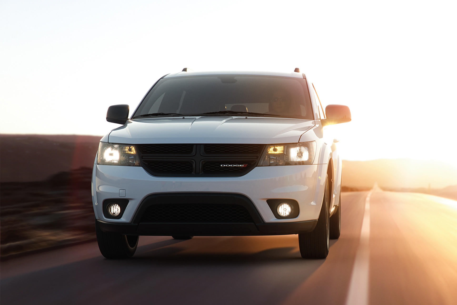 White 2019 Dodge Journey being driven down a freeway with hills and mountains in the background.