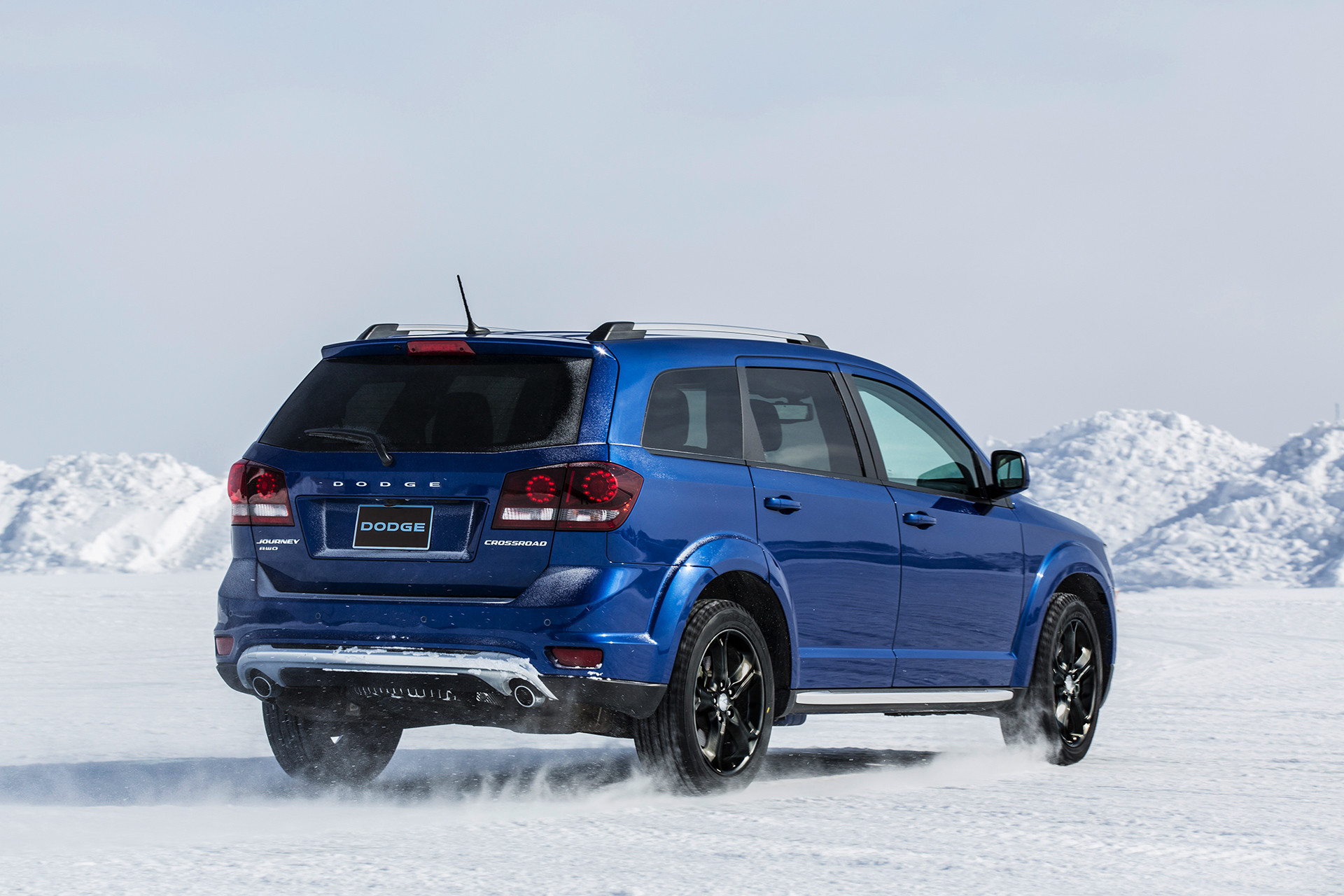 Vue arrière du Dodge Journey 2019, illustré en bleu, roulant dans la neige en montagne