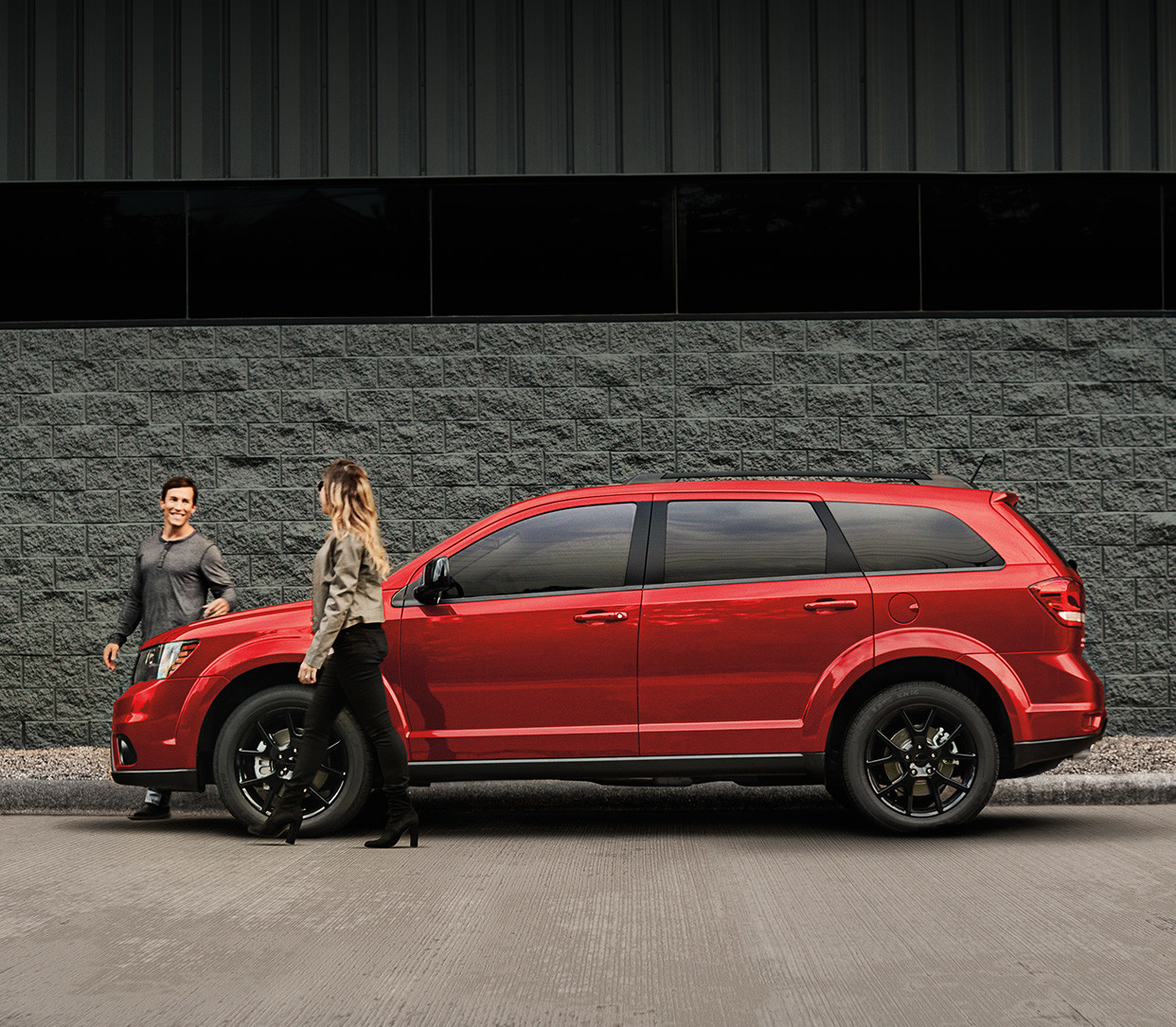 Red 2019 Dodge Journey, parked beside a grey building with two people walking away from the vehicle.