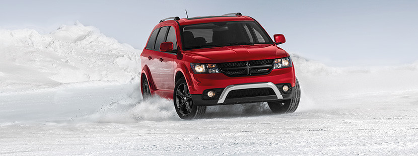 Vue de face de la Dodge Journey 2019, illustrée en rouge, roulant à travers un champ enneigé