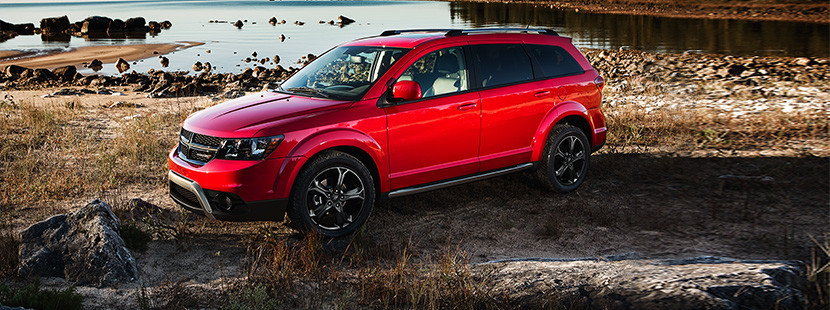 Red 2019 Dodge Journey, parked on a rocky lake shore.
