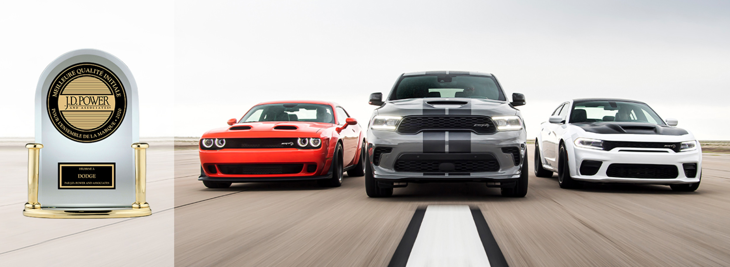 Vue de face d’une Dodge Challenger rouge, d’un Dodge Durango gris et d’une Dodge Charger blanche sur la route avec le logo de J.D. Power