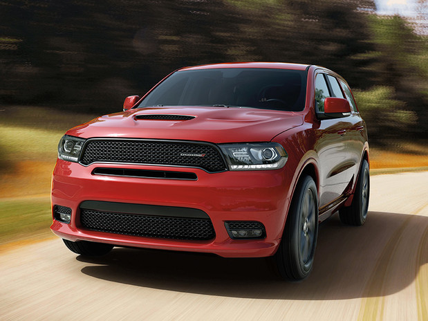 Dodge Durango conduit sur une route de campagne à travers des plaines tout en remorquant un bateau