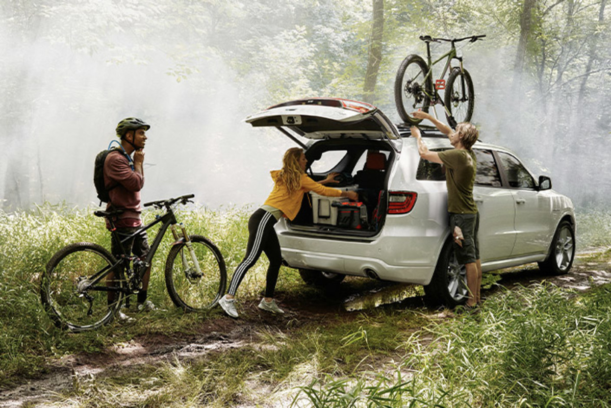 Recherchez votre offre Trois personnes remplissent le coffre d’un Dodge Durango dans une forêt.