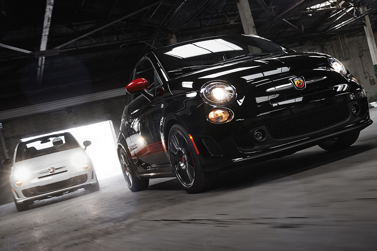 A black 2019 500 Abarth® driving through a warehouse with a white 2019 500 Abarth® following behind.