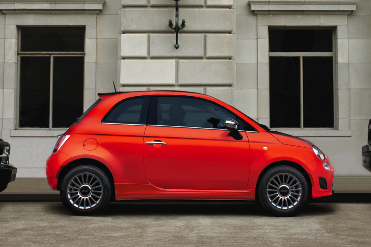 Orange 2019 FIAT® 500 parked on the side of the road between two black cars.
