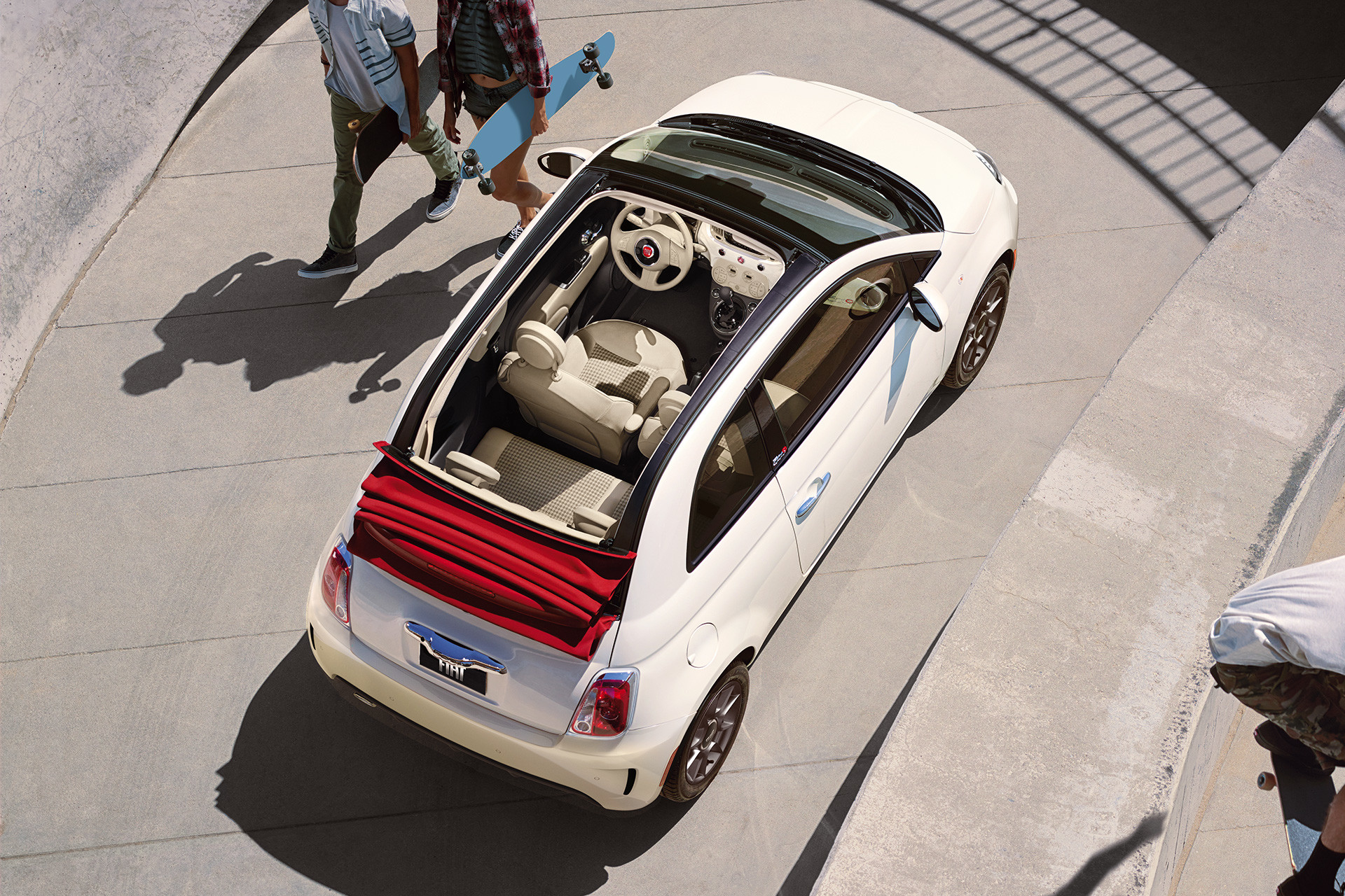 White 2019 Fiat 500 with its sunroof open, parked by a skate park.