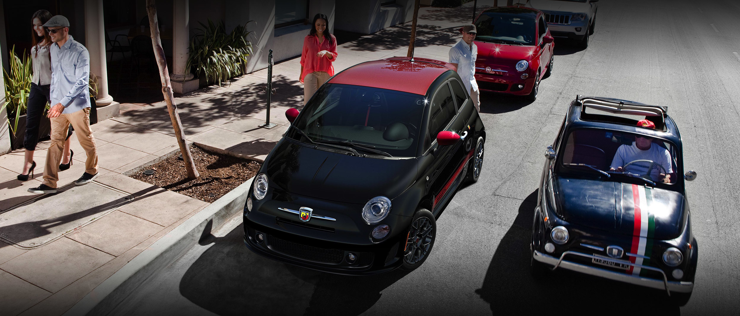 Black and red 2019 FIAT® 500 parked on the side of a street with a woman getting ready to enter the car.