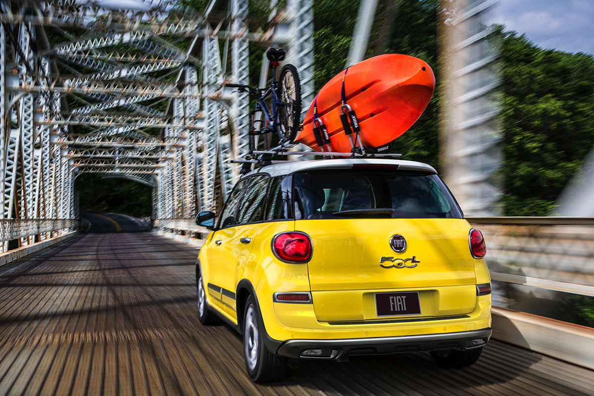FIAT 500L 2019 traversant un pont avec un kayak et un vélo sur le toit, illustrée en jaune