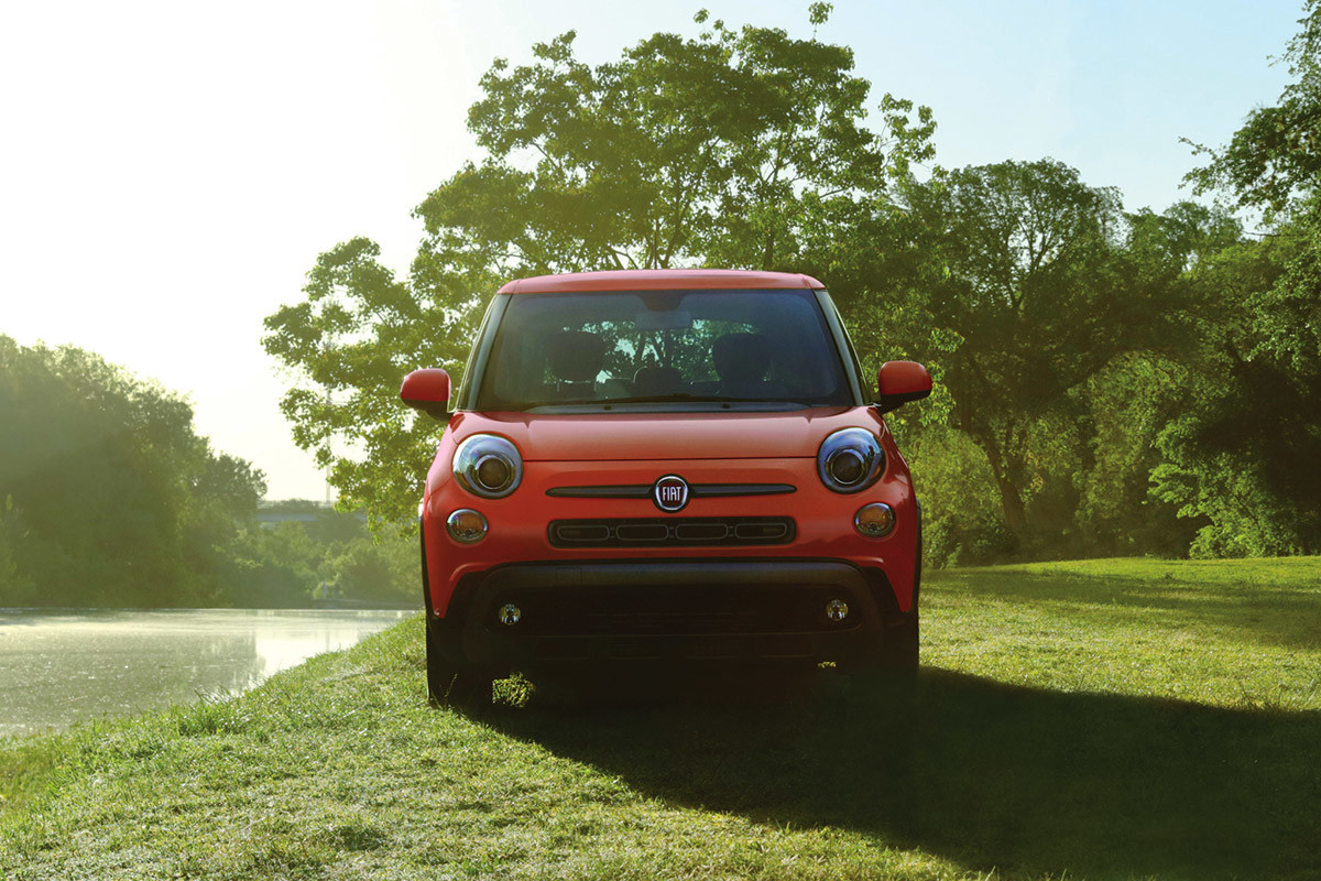 Vue avant de la FIAT 500L 2019 garée sur un terrain gazonné, illustrée en orange