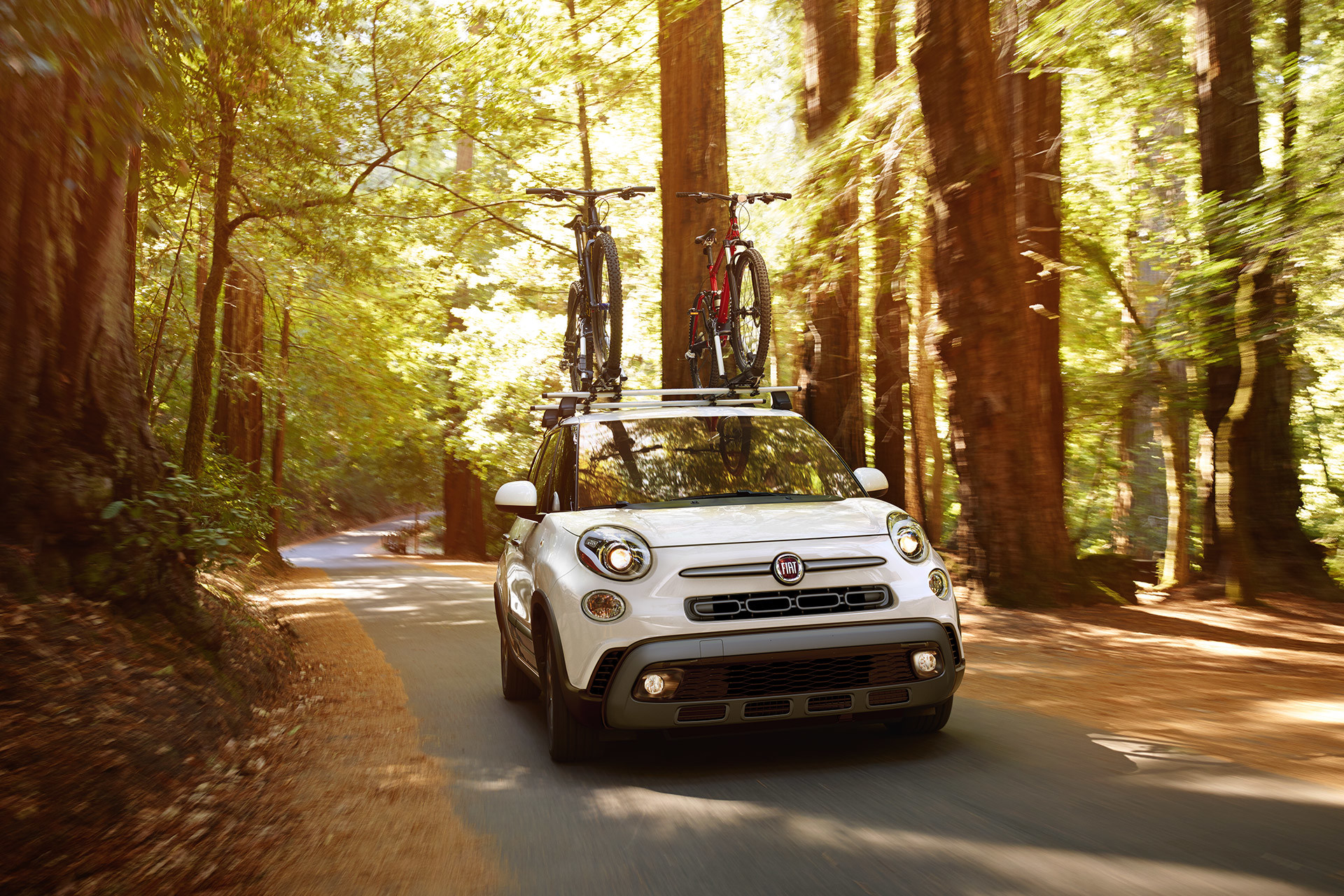 Vue avant de la FIAT 500L 2019 roulant sur une route de campagne, illustrée en blanc