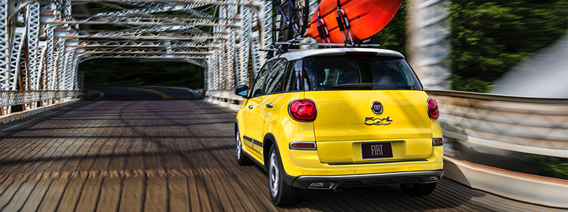 FIAT 500L 2019 traversant un pont avec un kayak et un vélo sur le toit, illustrée en jaune