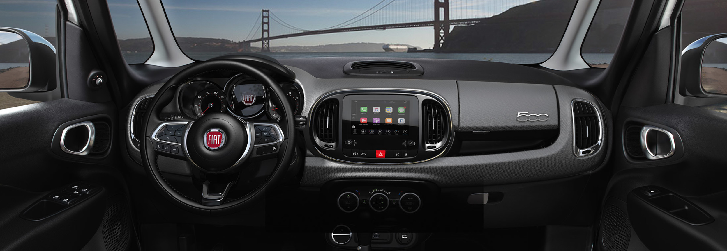 Tableau de bord avant, écran et console centrale de la FIAT 500L 2020 avec vue sur le pont Golden Gate.