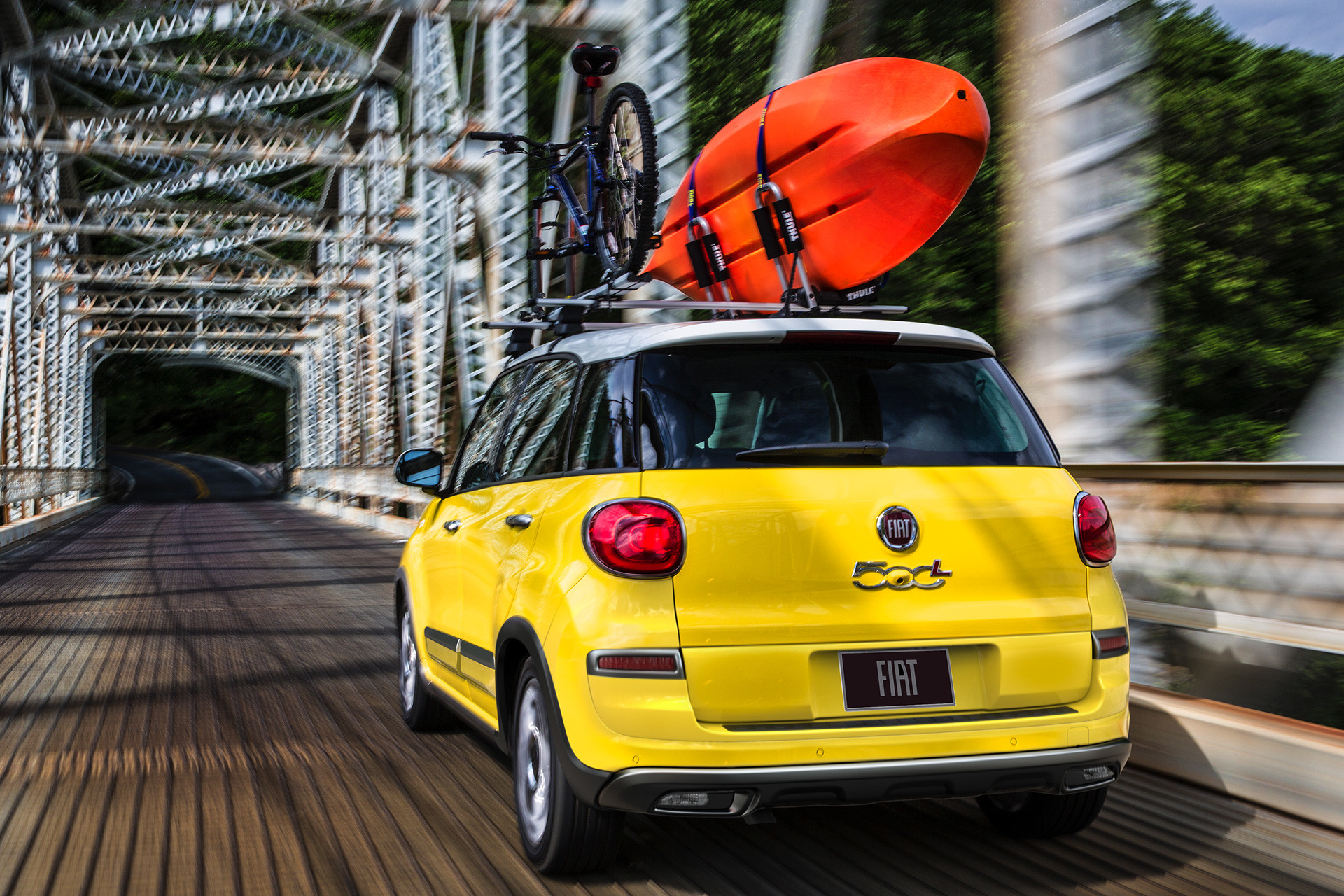 Rear view of the 2020 Fiat 500L with a kayak on the roof passing a bridge