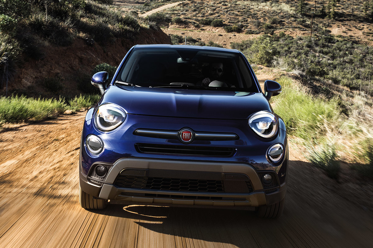 Une FIAT 500X 2020 bleu Italie roulant sur un chemin de terre dans la plaine