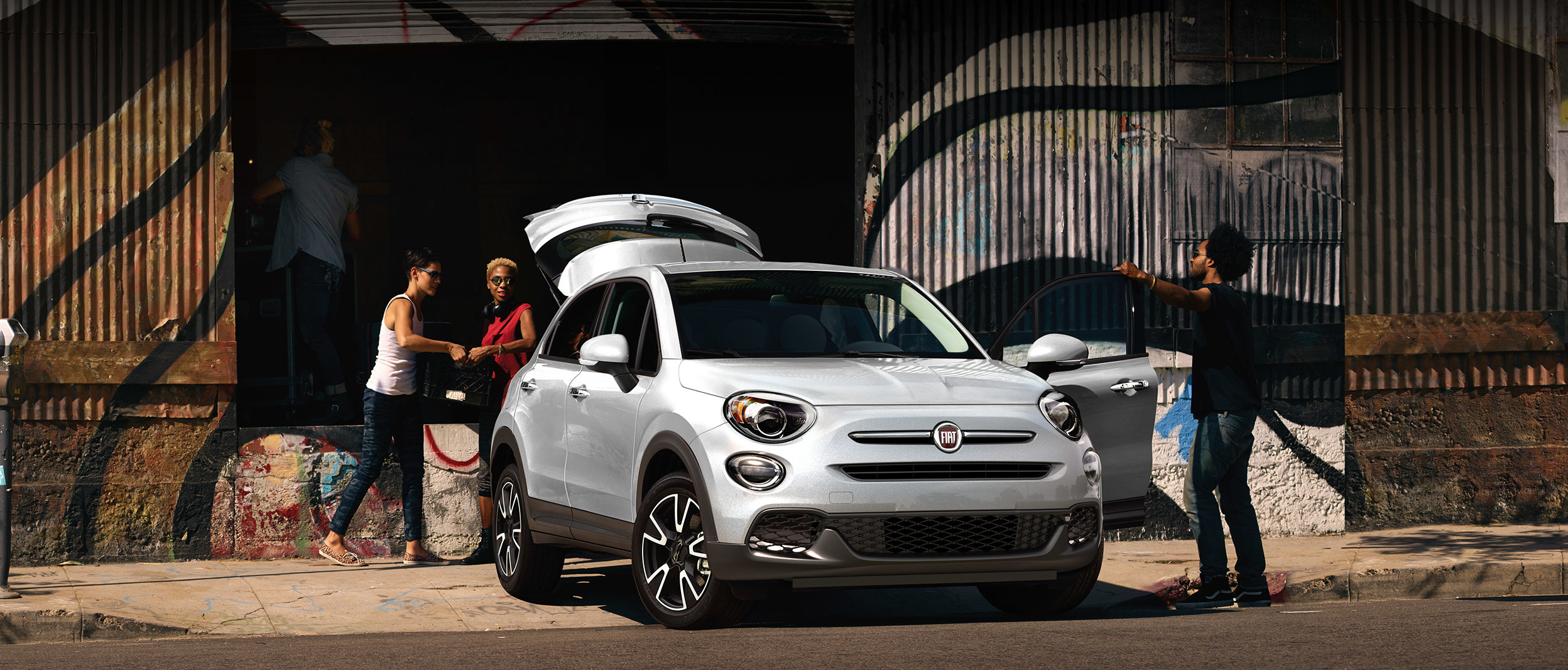Une FIAT 500X 2020 blanche garée devant un quai de chargement pendant qu’on y charge des marchandises