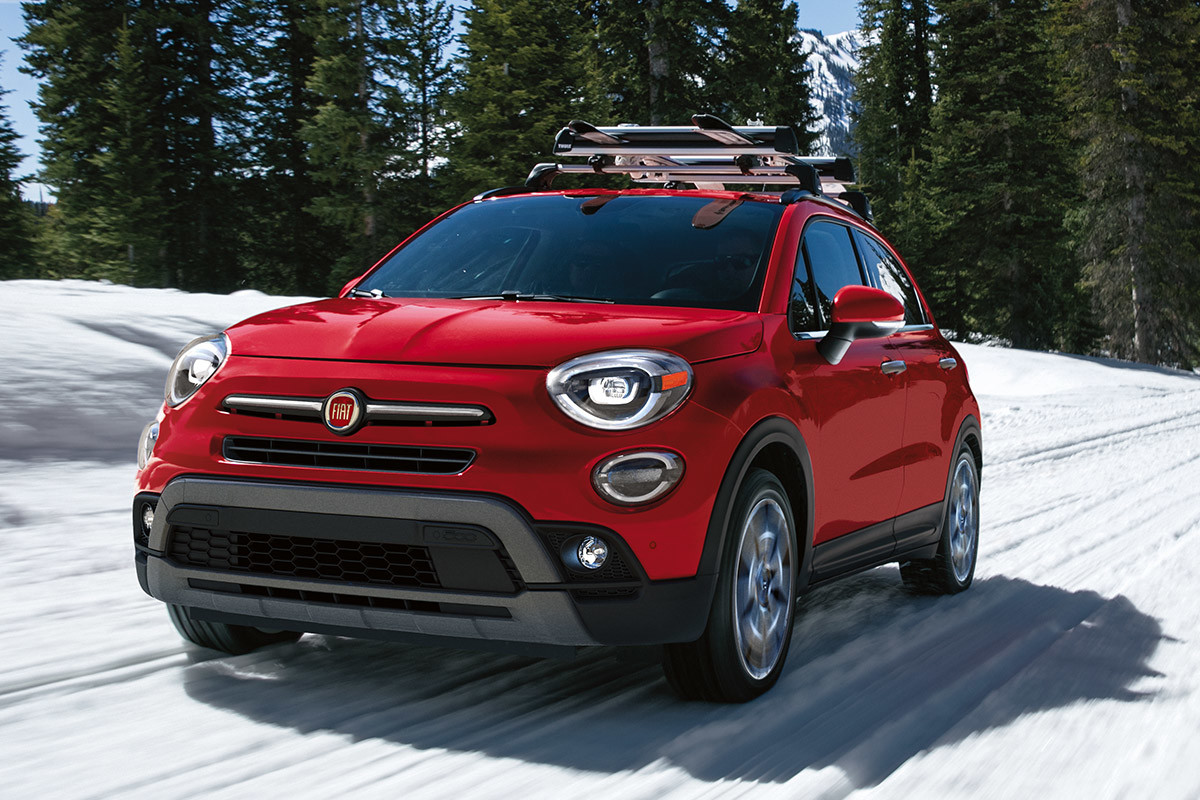 Side view of a red 2021 FIAT 500X with a Mopar ski-rack being driven on a snow-covered road