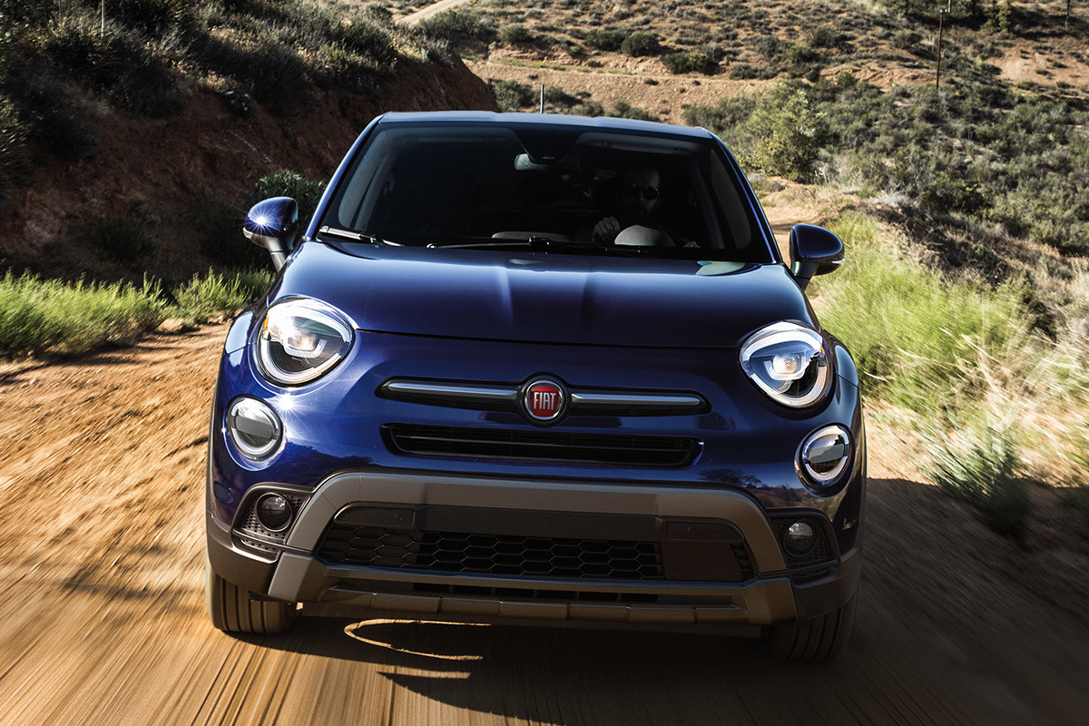 Front view of a blue 2021 FIAT 500X being driven on a dirt road in a desert landscape