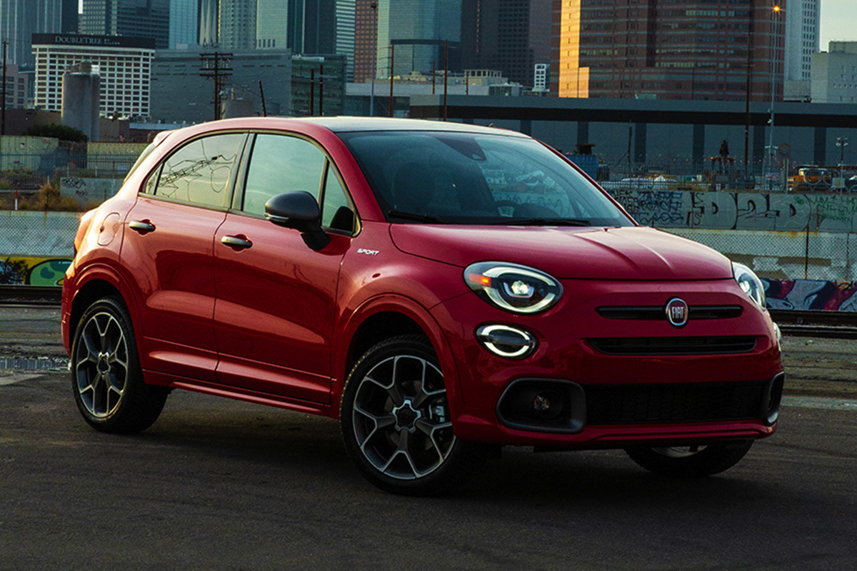 Side view of a parked red 2021 FIAT 500X Sport with a cityscape in background