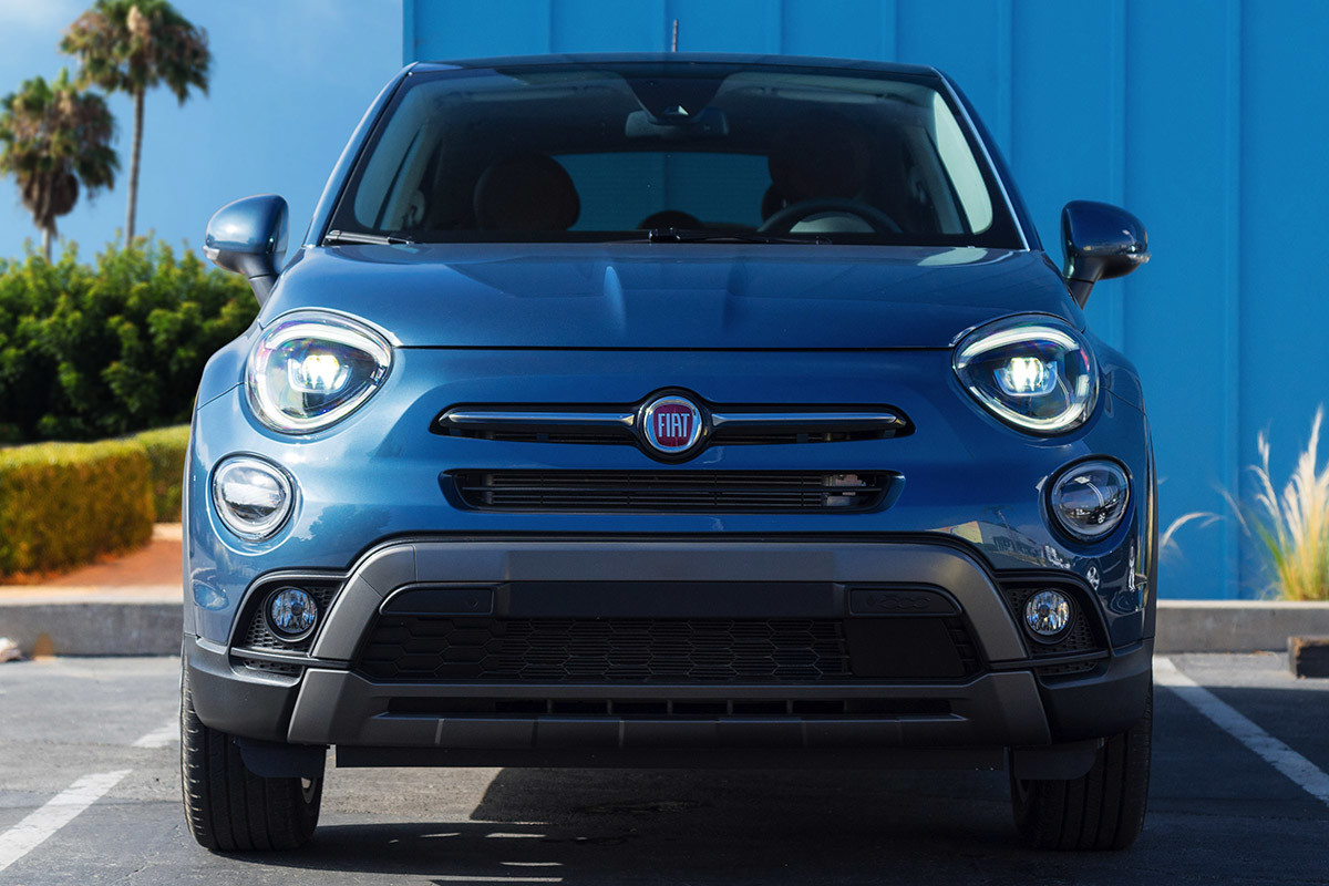Front view of a blue FIAT 500X in a parking spot with a blue wall behind it
