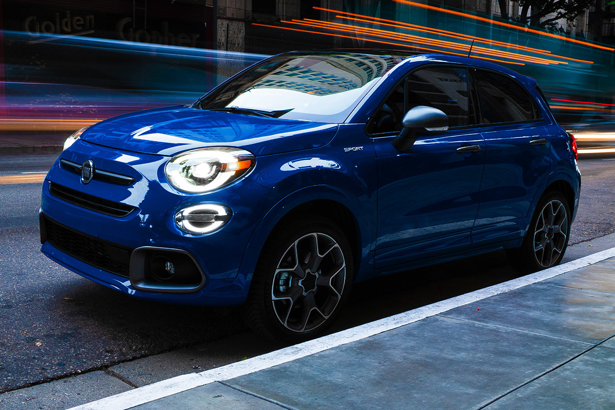 Side view of a blue 2021 FIAT 500X parked at the curb as cars speed by
