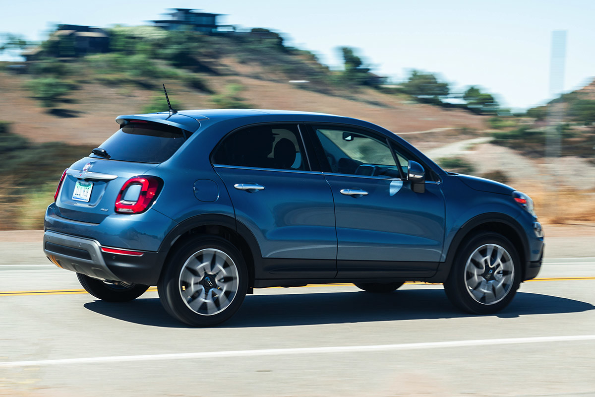 Side view of a blue FIAT 500X being driven on a road with desert in the background