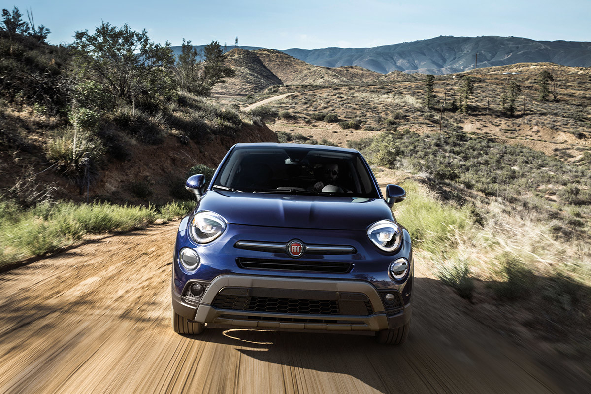 Une FIAT 500X 2022 bleue roulant sur un chemin de terre.
