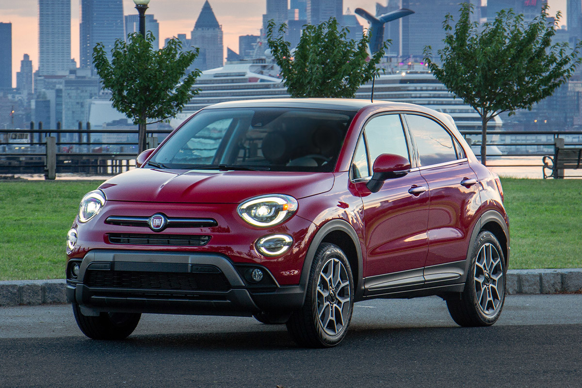 Une FIAT 500X 2022 rouge garée devant une ville.