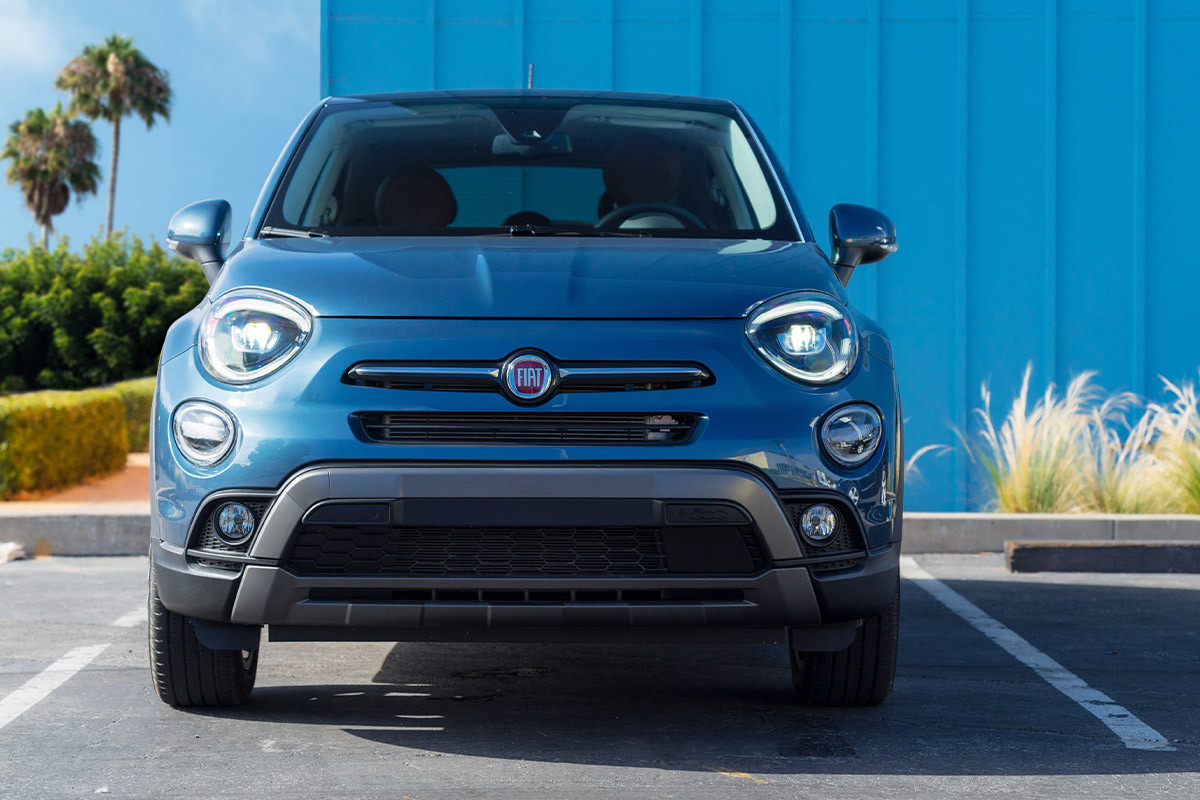 L'avant d'une FIAT 500X 2022 bleue garée devant un bâtiment en verre.
