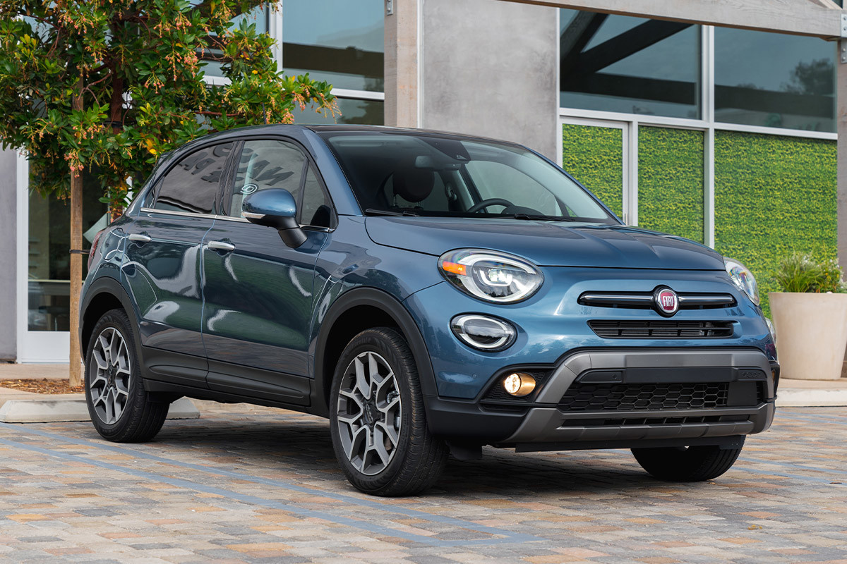 Une FIAT 500X 2022 bleue garée devant un bâtiment en béton.