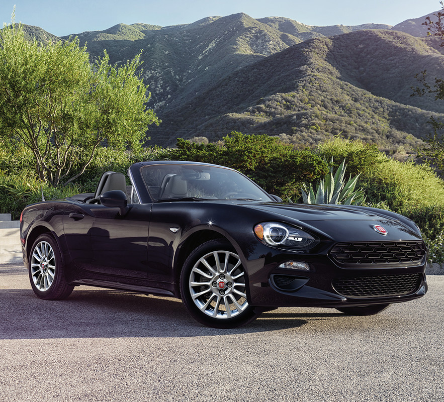 Black 2019 FIAT 124 Spider, parked on the pavement surrounded by trees