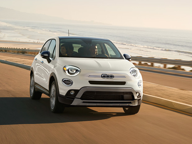 Une FIAT 500X 2022 blanche roulant sur une autoroute au bord de l’océan.