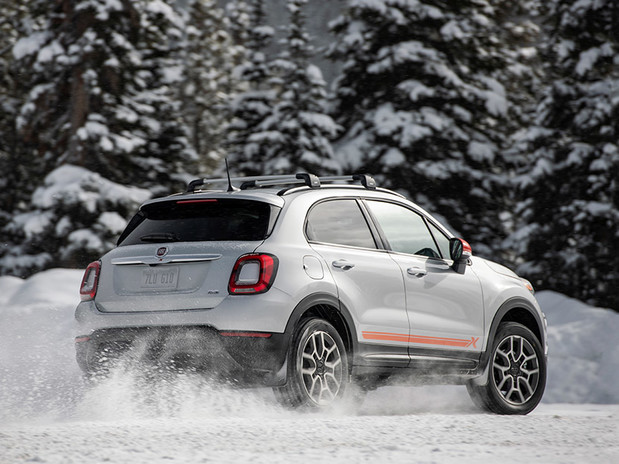 500X Adventurer Edition in Bianco Gellato driving through snowy clearing, pine forested mountains behind.