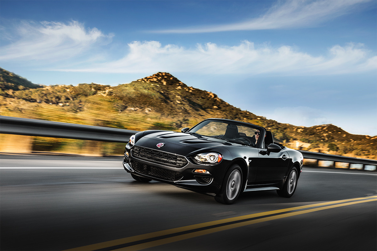 FIAT 124 Spider roulant sur la route, illustrée en noir